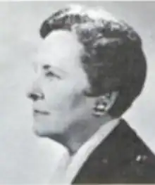 A middle-aged white woman, almost in profile, with short dark hair in a bouffant set