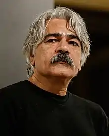 close-up of Kayhan Kalhor wearing a black t-shirt, looking right of camera with set expression