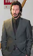 A candid portrait of Keanu Reeves wearing a gray suit.