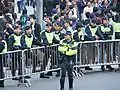 PTU officers stand guard behind a barricade.