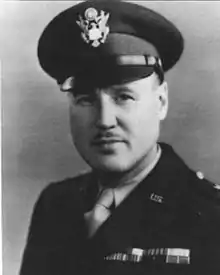 Head and shoulders of man in uniform with peaked cap and thin moustache.