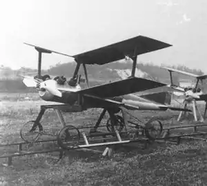 a small unmanned biplane aircraft resting on a pair of rails