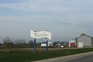 Welcome sign on WIS 54, farm in the background