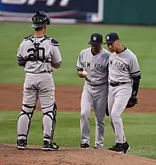 Wide shot of catcher Jorge Posada to the left with pitcher Mariano Rivera and shortstop Derek Jeter talking on the pitcher's mound.