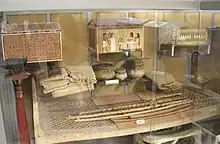 Numerous objects including a bed in a cramped display case