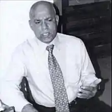 Black-and-white photograph of Mastana in a dress shirt and tie
