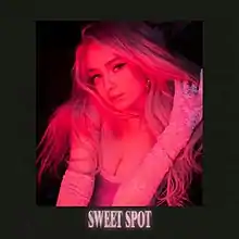 Kim Petras wearing a glove with her hand in her hair in pink lighting.