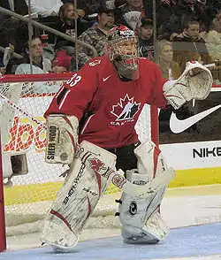 Woman wearing red hockey uniform and face mask
