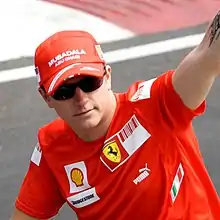 Kimi Räikkönen lifting his arm in the air while wearing a hat and sunglasses