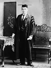 Black and white of a 17-year-old male dressed in a graduate's gown and cap with tassle