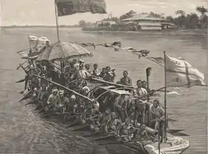 William Koko, Amanyanaboh of Nembe in his war canoe (seated under the umbrella)