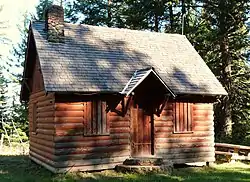 Photograph of a log cabin in a forest.