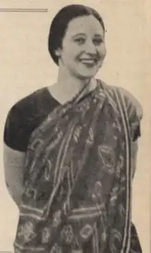 A smiling white woman with dark hair, wearing a printed sari