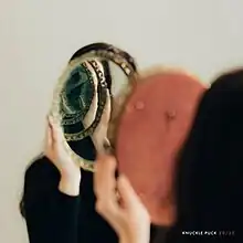 A person holding a mirror up to another mirror, creating the infinity mirror effect