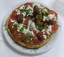 Dakos, traditional Cretan appetizer. Paximadi (hard bread) topped with fresh tomato, fetta cheese, oregano and olives drizzled with olive oil.