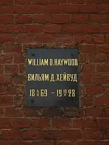 Plaque on a brick wall with inscription: William D. Haywood/Вильям Д. Хейвуд, 1869-02-04–1928-05-18