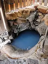An image of a hot spring bath carved out of rock in a wooden building.