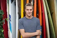 Kyle Thiermann in front of surf boards in his backyard