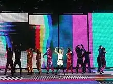 Minogue performing in a line of dancers in front of the LED background