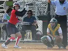 batter prepares for pitch with catcher squats behind her