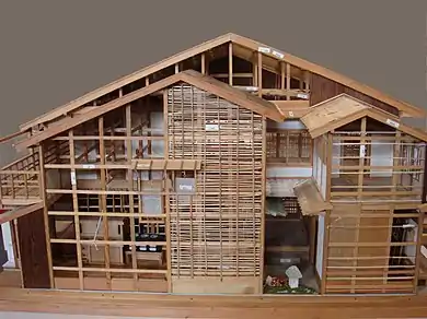 A model of a wood-frame house, with a 2-story-deep light well, surrounded by overlapping small skillion rooves at heights near the top of the ground floor, such that it has two layers of eaves.