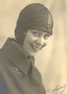 A woman wearing an overcoat and leather flying helmet