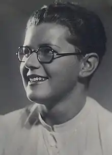 Portrait of a short-haired, woman wearing glasses and a white shirt with her head turned to the right offering a 3/4 profile