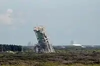 The MSS of Space Launch Complex 36A falls to the ground after critical supports are destroyed in a controlled explosion.