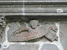 An angel holds a banner inscribed in Breton "AN:MARO:HAN:BARN:HAN:INFERN:IEN:PA:HO:SOING:DEN:E:TLE:CRENA FOL:EO NA:PREDER" which translates as  "La Mort, le Jugement, l'Enfer glacé, quand l'homme y songe, il doit trembler" or "Death, judgment, freezing hell. Think on that and fear it".