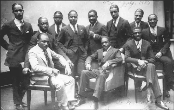 1925 photo taken at the Vox Phonograph Studio — Sam Wooding and his Orchestra; Seated, left to right: Tommy Ladnier (trumpet), John Warren (tuba) (behind), Sam Wooding (piano/leader), Willie Lewis (reeds), George Howe (1892–1936) (drums). Standing, left to right: Herb Flemming (trombone), Eugene Sedric (reeds), Johnny Mitchell (banjo), Bobby Martin (trumpet), Garvin Bushell (reeds), Maceo Elmer Edwards (1900–1988) (trumpet).Not pictured: Arthur Lange (1889–1956), Arthur Johnston (1898–1954), arrangers