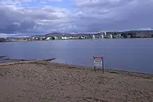 A metal sign erected on the sandy shores of the lake advises of the ban on water activity due to pollution