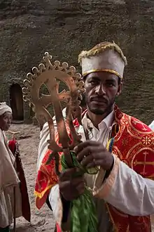 A priest stands with the Lalibela Cross after blessing Sunday worshippers.