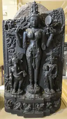 A basalt statue of Lalita flanked by Gaṇeśa and Kārttikeya