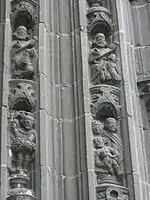 The scenes depicted here include Noah harvesting grapes from his vine and then Noah shown totally drunk! Above the biblical scenes, the voussure continues with the Evangelists. On the left side of the arch, Luke is shown with his attribute the lion and John with his attribute, a young boy. Mark and Matthew are depicted on the right side of the arch. After the Evangelists thirty one angels occupy the voussure, praying, playing instruments or holding their censers; a veritable "heavenly choir". Above the voussures are two sculptures. One is a small statue of a saint holding a book and the other is a saint with hands crossed against her chest.
