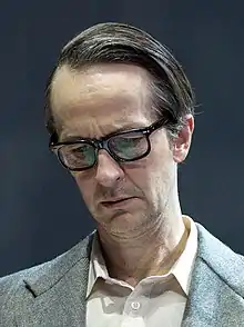 close-up of Lars Brygmann wearing glasses, looking down