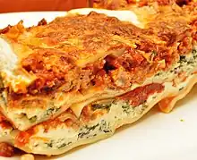 Close-up profile view of a lasagna casserole, showing the layers of sauce, cheese and other ingredients
