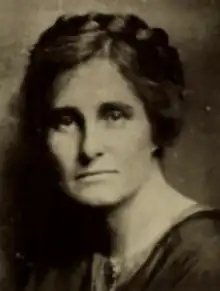 A white woman with her hair side-parted and braided over the crown