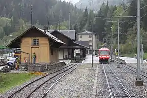 Red-and-white train on double track with side platforms