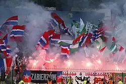 A large number of supporters, waving flags, displaying banners and setting off flares.