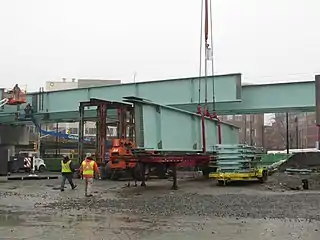 A large steel beam being lifted onto a viaduct