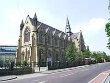 imposing neo-Gothic sandstone chapel, with modern buildings in the background