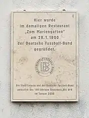 German plaque outside Zum Marriengarten, which translates into English as "Here, in the former 'Zum Marriengarten' restaurant, the German Football Association was founded on 28 January 1900." Underneath this text is an inscription noting that the German Football Association and city of Leipzig put up this plaque on the 100th anniversary in the year 2000.