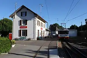 Red-and-white train next to platform with three-story building