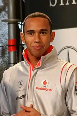 Lewis Hamilton wearing a silver clothing and smiling at the camera
