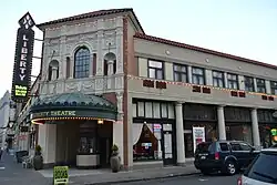 Photograph of the Astor Building, a two-story commercial building with an intricate theater entrance facing onto a city street corner
