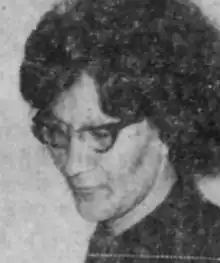 A Native American woman with dark hair in a bouffant hairstyle, wearing cat-eye glasses