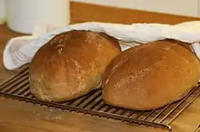 Two freshly baked loaves of limpa bread on a cooling rack