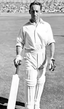 Hassett in cricket whites and carrying a cricket bat walks off of a cricket ground