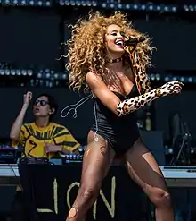 a woman with blonde curly hair performs on stage