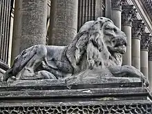 A life-sized statue of a lion, its face eroded from weathering